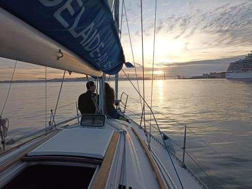 リスボンにあるBe Local - Holidays on the Santa Maria boat with free sunset tour in Lisbonの水上の帆船に腰掛けている男女