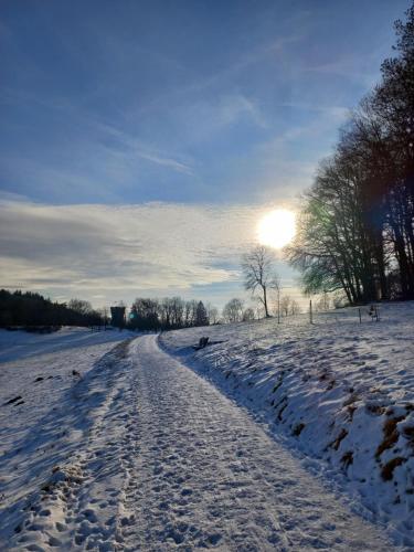 a snow covered field with the sun in the distance at Dorfliebe Winterkasten in Lindenfels