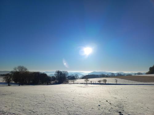 a snow covered field with the sun in the sky at Dorfliebe Winterkasten in Lindenfels
