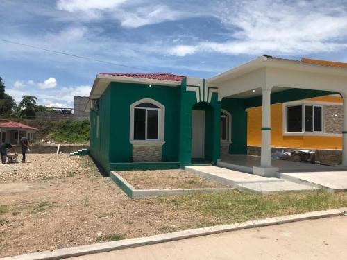 uma pequena casa verde e amarela num quintal em Tu mejor opción em Juticalpa