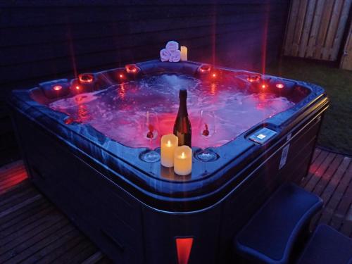 a hot tub with a bottle of wine and lights at "Huisje op de Veluwe" met privé Jacuzzi en Bar! in Ermelo