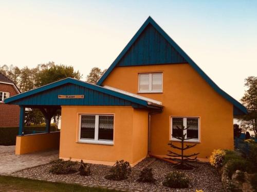 una pequeña casa naranja con techo azul en Feriengrundstück direkt am See, en Dabel