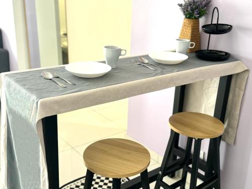 a counter with two stools and a table with plates and bowls at Ipoh Horizon Skypool Town Suites 4-11pax by IWH Suites in Ipoh