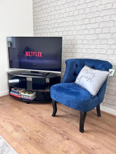 a blue chair with a pillow in front of a tv at Cathedral Walk 3 Bed Coachhouse in Lichfield