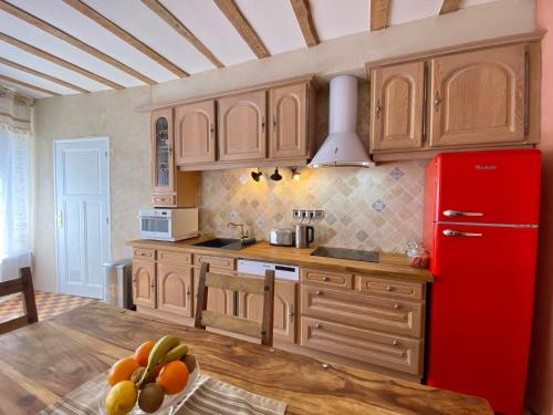 eine Küche mit einem roten Kühlschrank und Holzschränken in der Unterkunft La Maison des Templiers ~ Ostal Médiéval ~ Logis enchantés in Carcassonne