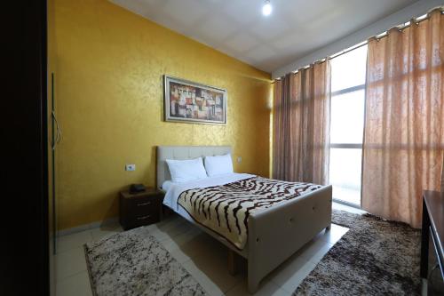 a bedroom with a bed with yellow walls and a window at HOTEL GJUTA in Tirana