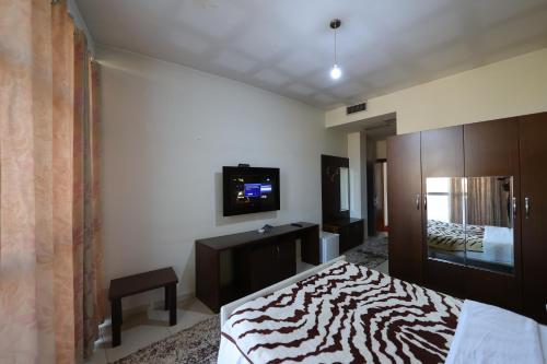 a bedroom with a bed and a tv on the wall at HOTEL GJUTA in Tirana