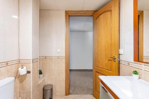 a bathroom with a toilet and a wooden door at Amplio y tranquilo piso para disfrutar del centro de Málaga in Málaga