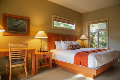 a bedroom with a bed and a desk and a chair at Long Beach Lodge Resort in Tofino