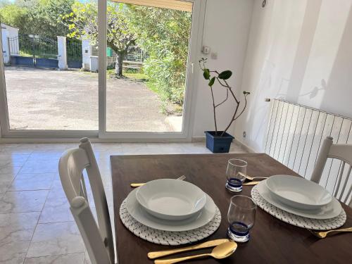 une table en bois avec des assiettes et des serviettes blanches dans l'établissement Logement provençal au calme à 20 min d’Avignon, à Lirac