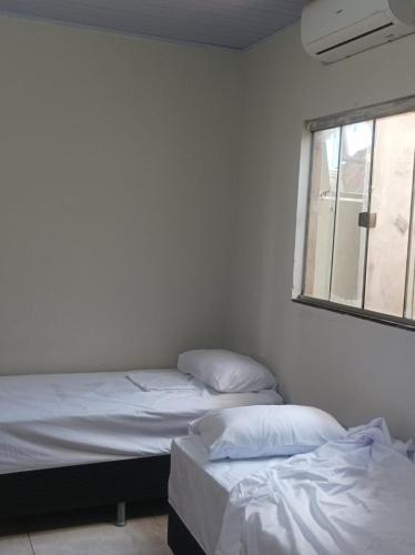 two twin beds in a room with a window at HOTEL CENTRAL in Chapadão do Céu