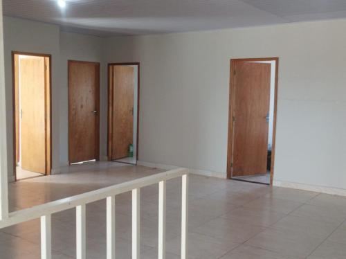 an empty room with three doors and a tile floor at HOTEL CENTRAL in Chapadão do Céu