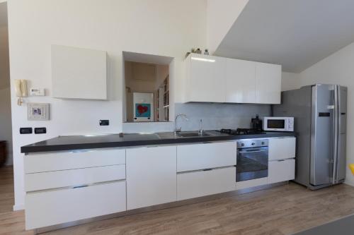 a kitchen with white cabinets and a stainless steel refrigerator at Casa Vecchia Quercia in Assago