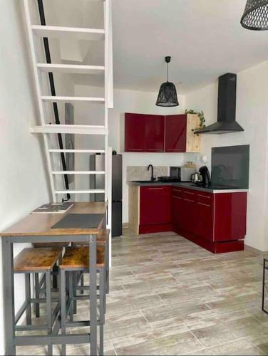 une cuisine avec des placards rouges, une table et un escalier dans l'établissement Appartement Centre ville, à Saint-Amand-Montrond