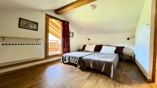 une chambre avec deux lits et une grande fenêtre dans l'établissement Résidence Dame Blanche - DBAC32 - APPT DUPLEX DANS CHALET - 4 CHAMBRES 10 PERSONNES - Secteur 1800 MAE-7734, à Narreyroux