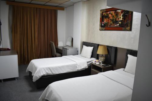 a hotel room with two beds and a chair at Hotel Sinaia Palace in Erbil