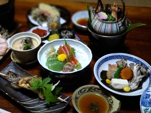 una mesa con platos de comida y tazones de sopa en Shimaonsen AYAMEYA Ryokan - Vacation STAY 20622v, en Shima