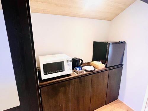 eine Mikrowelle und ein Kühlschrank auf einem Holzschrank in der Unterkunft CONNECT, - Vacation STAY 33451v in Arita