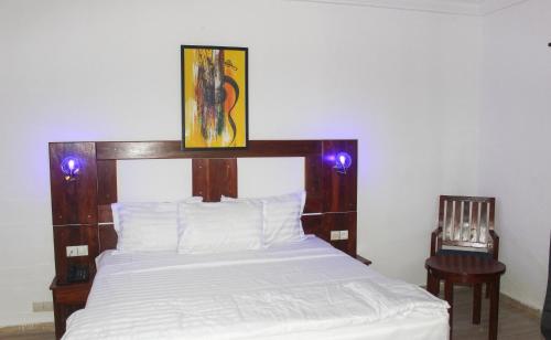 a bedroom with a bed with a wooden headboard and purple lights at Hotel BKBG Benin in Cotonou
