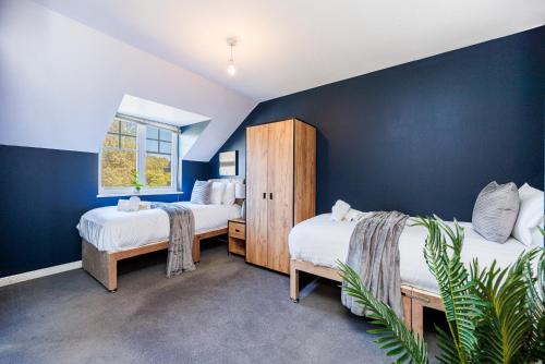 4 Bed Townhouse in Uxbridge Ideal For Families or Contractors في هيلينغدون: غرفة نوم بسريرين وجدار ازرق