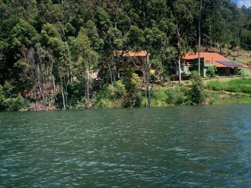 une maison sur la rive d'un lac avec un bâtiment dans l'établissement Casa Apu Honey Moon Suite Pague duas noites minimo e a terceira e brinde menos feriados, à Natividade da Serra