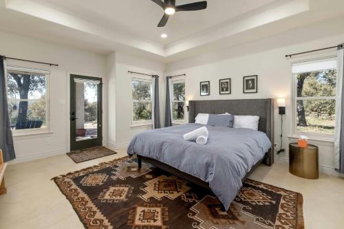 a bedroom with a large bed and windows at Hill Country Norwood House- 13 Acres, Private Pool and Pet Friendly! in Dripping Springs