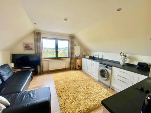 a living room with a couch and a washer and dryer at Brohar Annexe in Inverness
