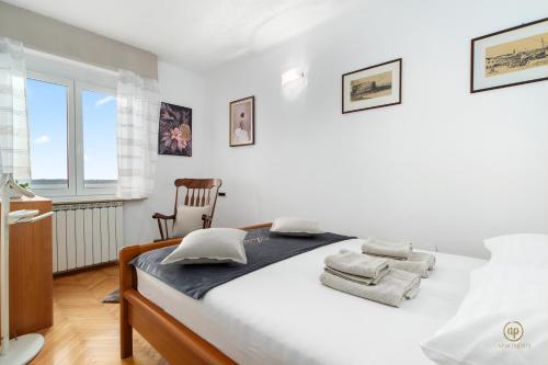 ARIA Superior Apartment, Seaview & Wellness في بوروتوروج: غرفة نوم بيضاء بسرير وكرسي