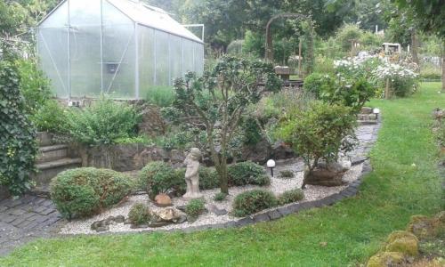 a garden with a glass greenhouse in the background at Appartement in Berlingen mit Garten, Terrasse und Grill in Berlingen