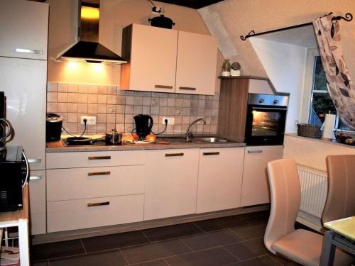 cocina con armarios blancos, fregadero y fogones en Ferienwohnung für 6 Personen in Berlingen, Rheinland-Pfalz en Berlingen