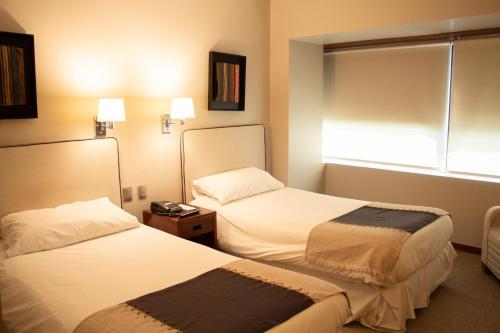 a hotel room with two beds and a window at Almacruz Hotel y Centro de Convenciones (Ex Galerías) in Santiago