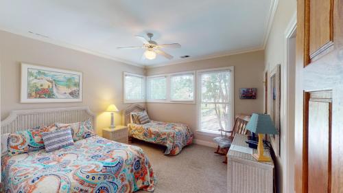 a bedroom with a bed and a chair and windows at Golf and Beach: 2BR Lakeside Villa with Lake Views in Pawleys Island