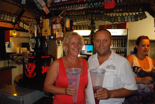 a man and a woman holding up cups in a bar at Oppi-Koppi Rest Camp in Kamanjab