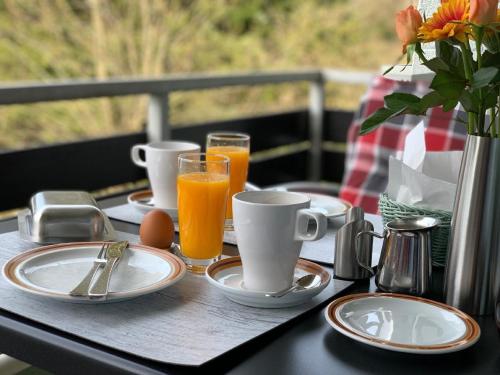 einen Tisch mit Teller und Tassen Orangensaft in der Unterkunft Luxusfewo mit IR-Wärmekabine und Boxspringbett für Zwei in Goslar