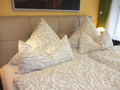 ein Bett mit weißen Kissen darüber in der Unterkunft Luxusfewo mit IR-Wärmekabine und Boxspringbett für Zwei in Goslar