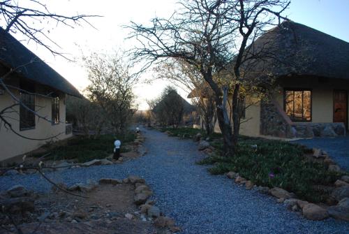a gravel path next to a house and a building at Oppi-Koppi Rest Camp in Kamanjab