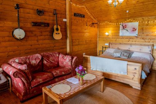 a living room with a couch and a bed at Blossom Cabin - Little log Cabin in Wales in Newtown