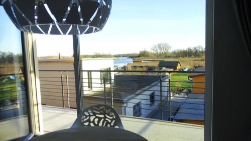 une personne assise sur un balcon donnant sur l'eau dans l'établissement Ferienwohnung Wünnowblick mit Sauna, à Röbel