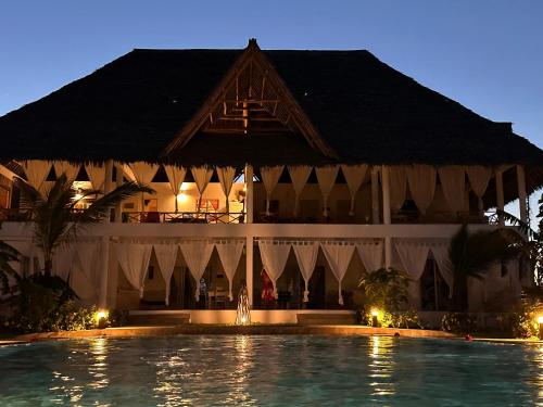 a resort with a swimming pool in front of a building at Nadia&Ale House - Maisha Resort in Watamu
