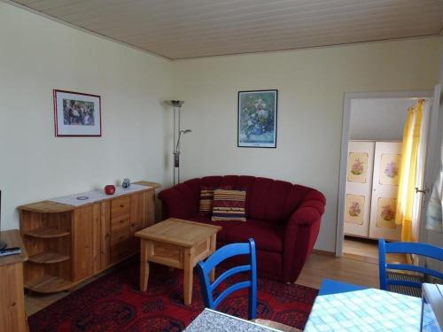 ein Wohnzimmer mit einem roten Sofa und einem Tisch in der Unterkunft Kleines Ferienhaus im Garten- Haus Holzheimer mit dem einzigartigen Blick über Bad Kissingen bis zur Rhön in Bad Kissingen
