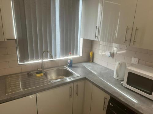 En-suit double bedroom with bathroom in Manchester في مانشستر: مطبخ مع حوض وميكروويف