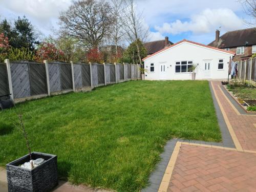 a backyard with a fence and green grass at Detached Flat in Leeds, Free WIFI and parking, Pool table, 75 inch tv, Netflix, Disney plus in Moortown