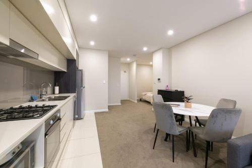 cocina y comedor con mesa y sillas en Comfortable apartment, near Parramatta CBD!, en Merrylands