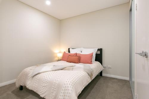 Un dormitorio con una cama con almohadas rosas. en Comfortable apartment, near Parramatta CBD!, en Merrylands