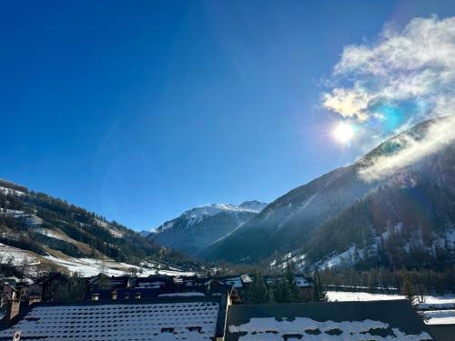 a view of a snowy mountain valley with the sun in the sky at Studio Pablotin du Queyras in Abriès