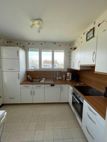 une cuisine avec des armoires blanches et des appareils électroménagers blancs dans l'établissement Barneville, à Barneville-Carteret