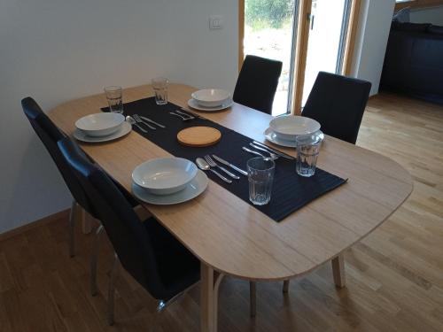 una mesa de madera con sillas, platos y vasos. en Dantin guest house en Prvačina
