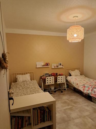 um quarto com duas camas e uma mesa com livros em Maison JO 2024 Clamart em Clamart