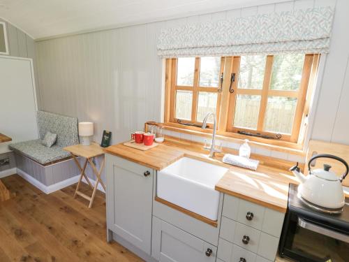 cocina con fregadero blanco y ventana en Shepherds Hut at Lythwood, en Shrewsbury