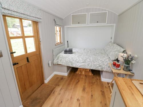 1 dormitorio pequeño con 1 cama y suelo de madera en Shepherds Hut at Lythwood, en Shrewsbury